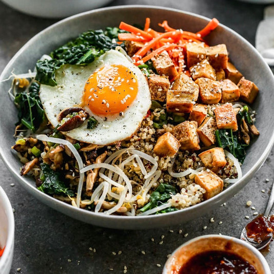 Tofu Bibimbap with Fried Egg and Brown Rice topped with assorted vegetables and tofu.